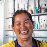 Una mujer se ríe detrás de la barra de su restaurante.