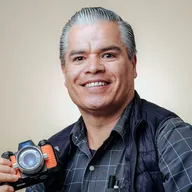 Un fotógrafo sonríe con su cámara.